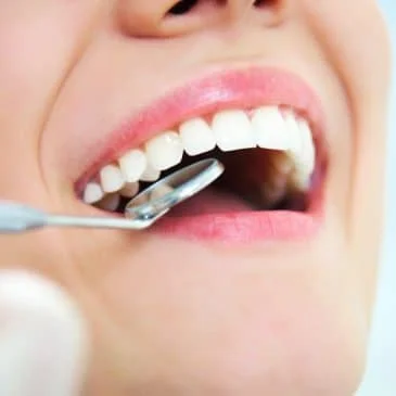 Close-up of a patient's mouth during a dental examination, showcasing healthy teeth and a dental mirror, highlighting the importance of recognizing oral health signs.