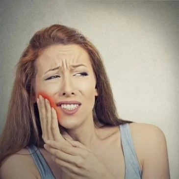 Woman experiencing facial pain and discomfort in jaw, indicating symptoms of TMJ disorder.