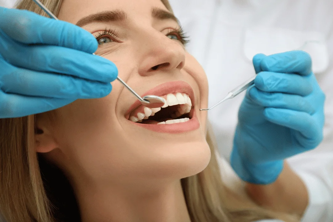 Woman smiling in dental chair during cosmetic dentistry consultation with dental tools, highlighting the importance of oral health and confidence.
