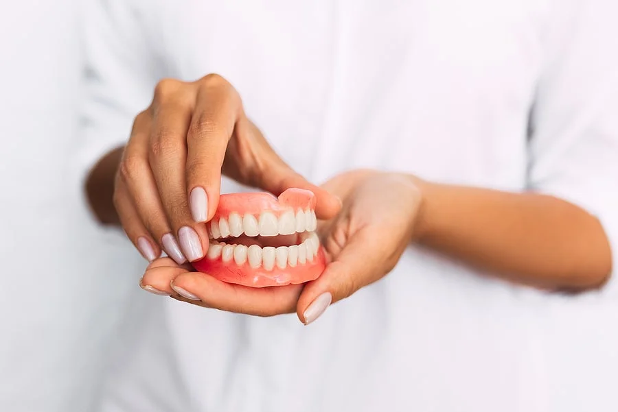 Hands holding upper and lower removable dentures
